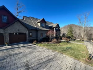 Photo of a ranch-style home with a new roof and cobblestone-style driveway