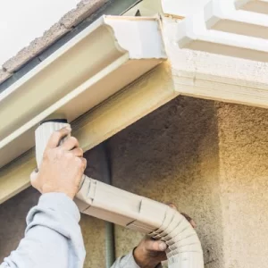 Gutter professional installing a downspout to a residential gutter system in North Carolina