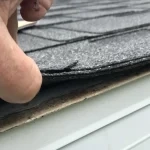Inspector checking under the shingles during a roof inspection
