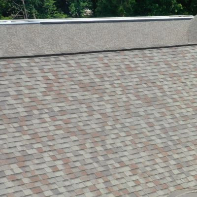 Close-up view of a roof with multi-colored asphalt shingles in various shades of gray and brown